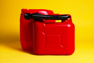 Photo of Two red plastic canisters on yellow background