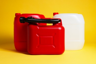 Photo of Three colorful plastic canisters on yellow background