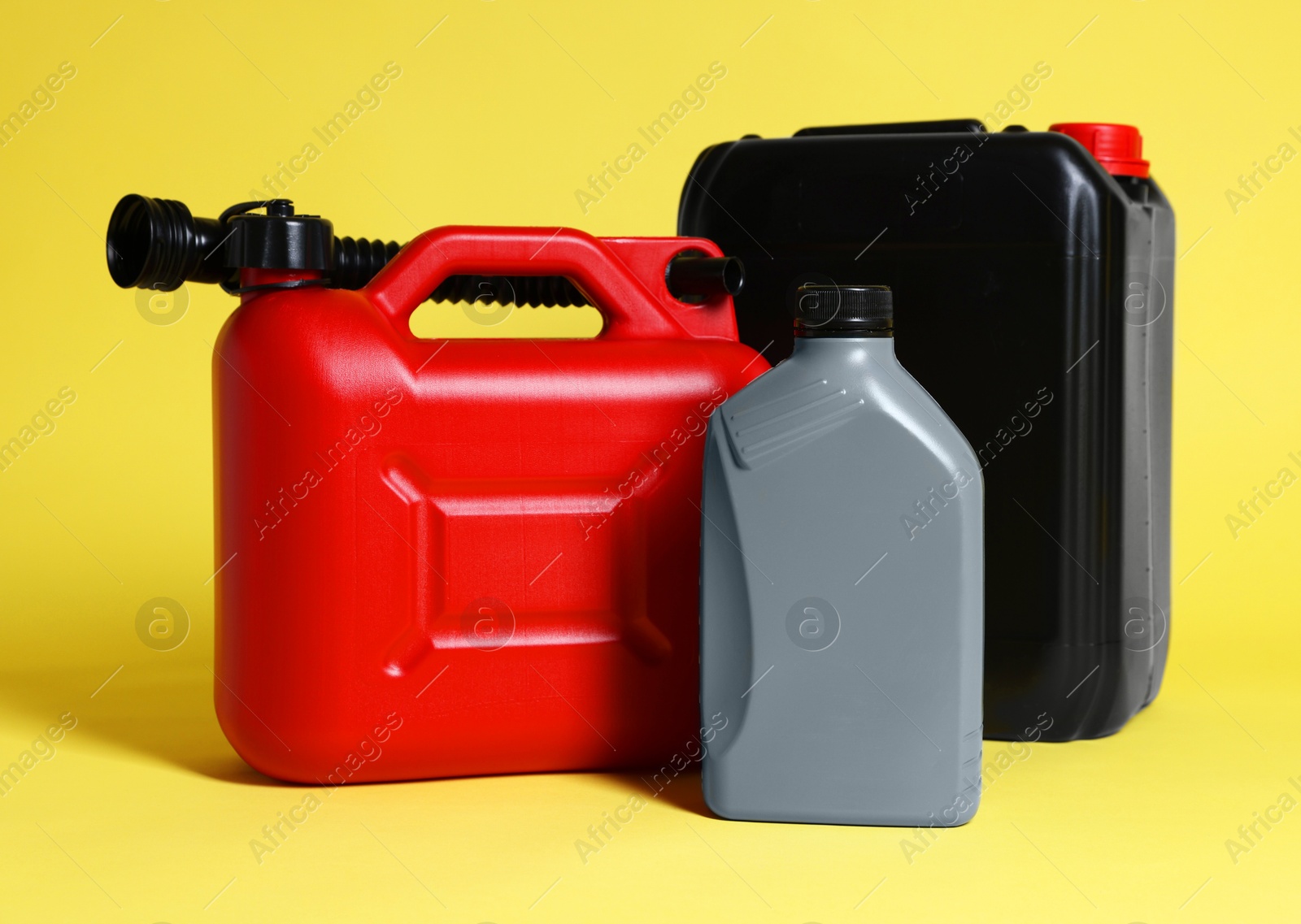 Photo of Three colorful plastic canisters on yellow background