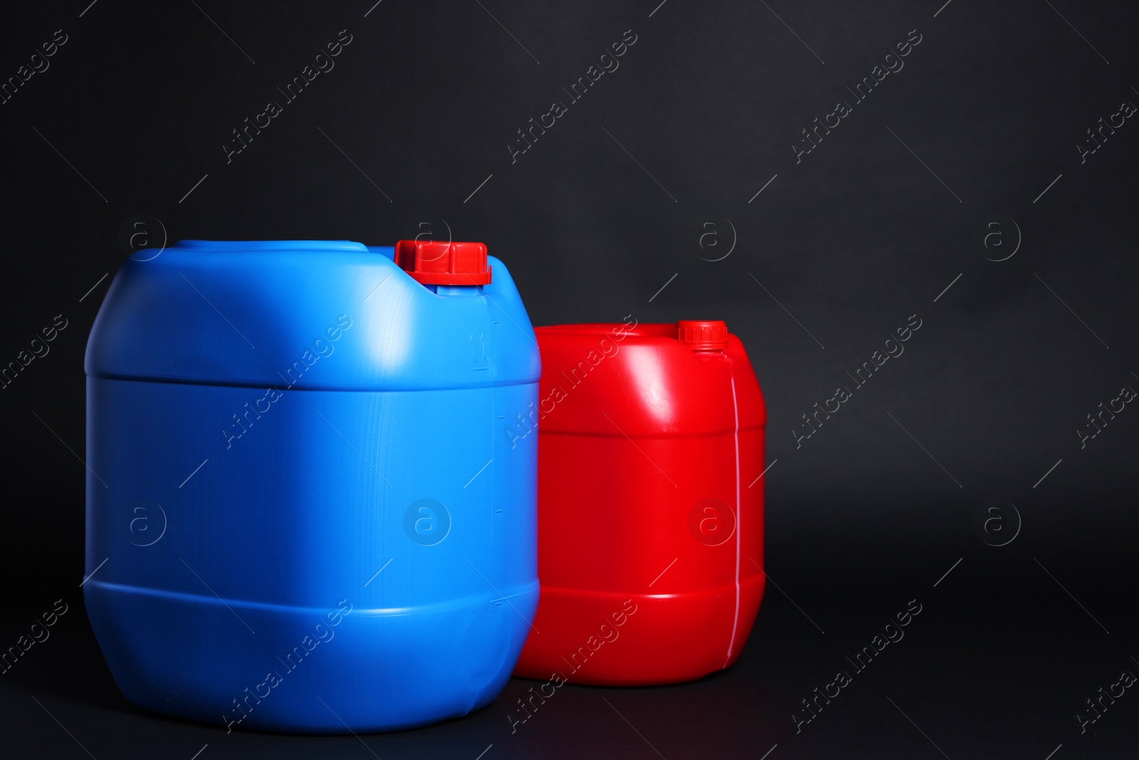 Photo of Two plastic canisters on black background, space for text