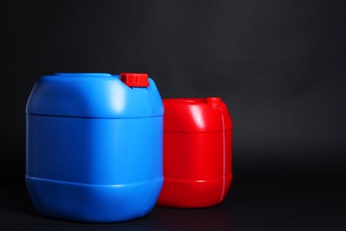 Photo of Two plastic canisters on black background, space for text