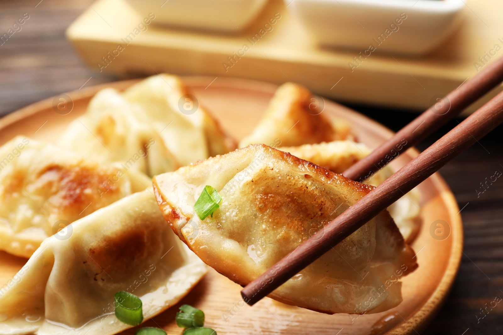 Photo of Eating fried gyoza dumplings at wooden table, closeup