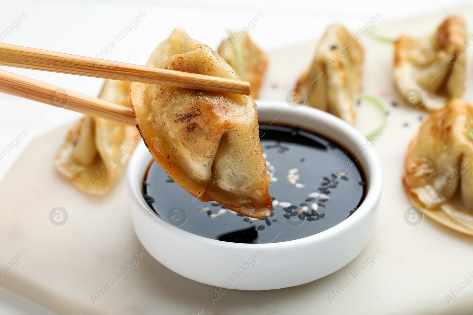 Photo of Eating fried gyoza dumplings at white table, closeup