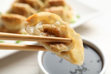 Photo of Eating fried gyoza dumplings at white table, closeup