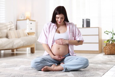 Photo of Beautiful pregnant woman with cute belly on floor at home