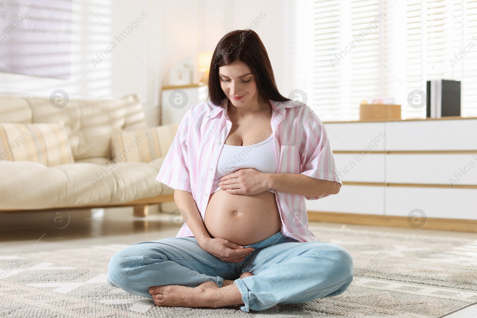 Photo of Beautiful pregnant woman with cute belly on floor at home