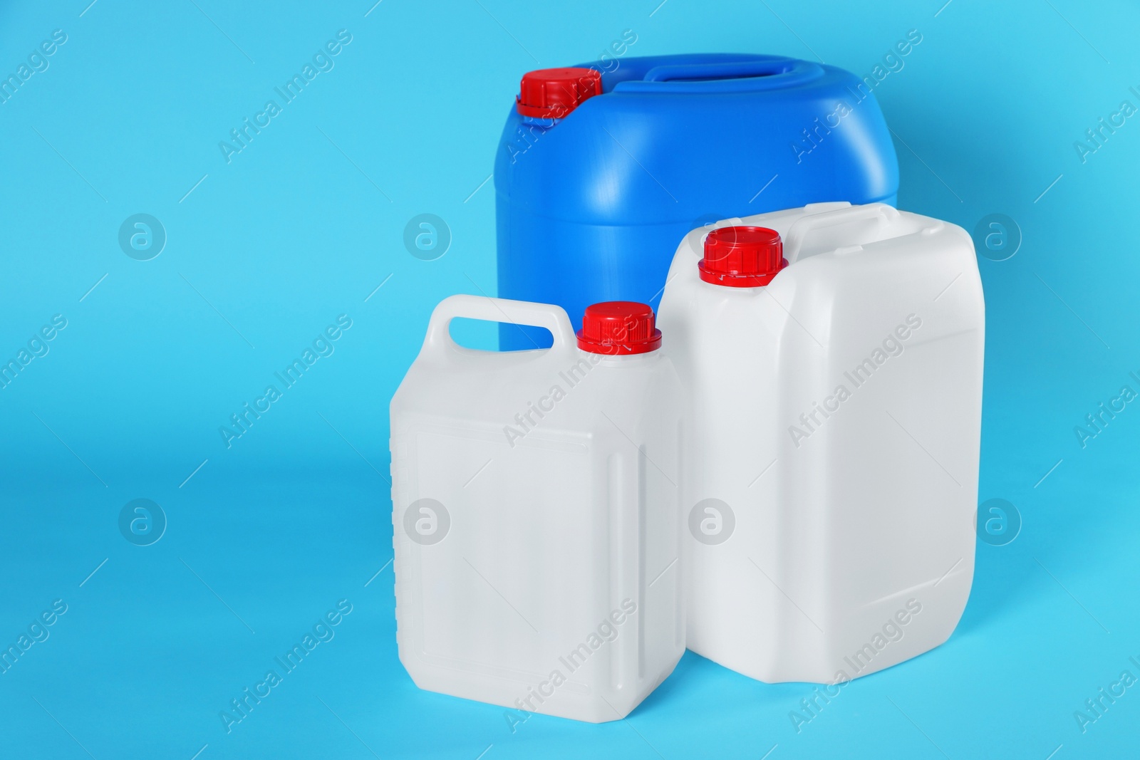 Photo of Different plastic canisters on light blue background, space for text