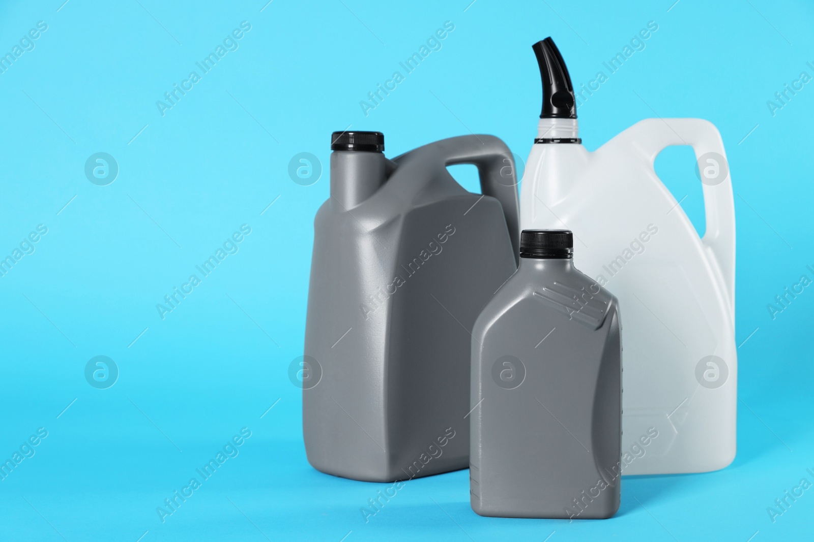 Photo of Different plastic canisters on light blue background, space for text