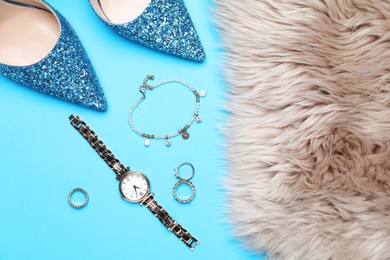 Photo of Beautiful shoes, faux fur and stylish accessories on light blue background, flat lay