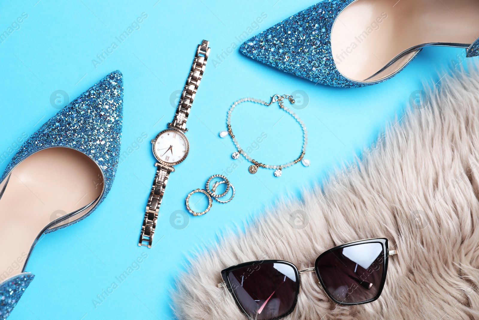 Photo of Beautiful high heeled shoes, faux fur and stylish accessories on light blue background, flat lay