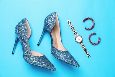 Photo of Beautiful high heeled shoes and stylish accessories on light blue background, flat lay