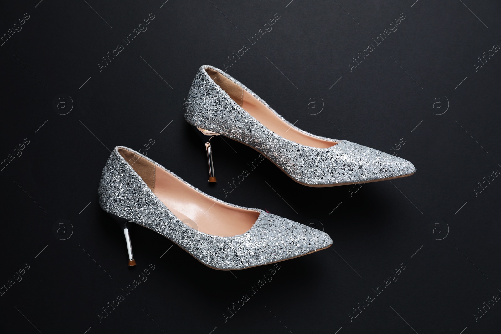 Photo of Beautiful high heeled shoes on black background, top view