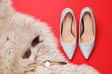 Photo of Beautiful high heeled shoes, stylish accessories and faux fur on red background, flat lay