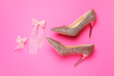 Photo of Beautiful high heeled shoes and bows on pink background, flat lay