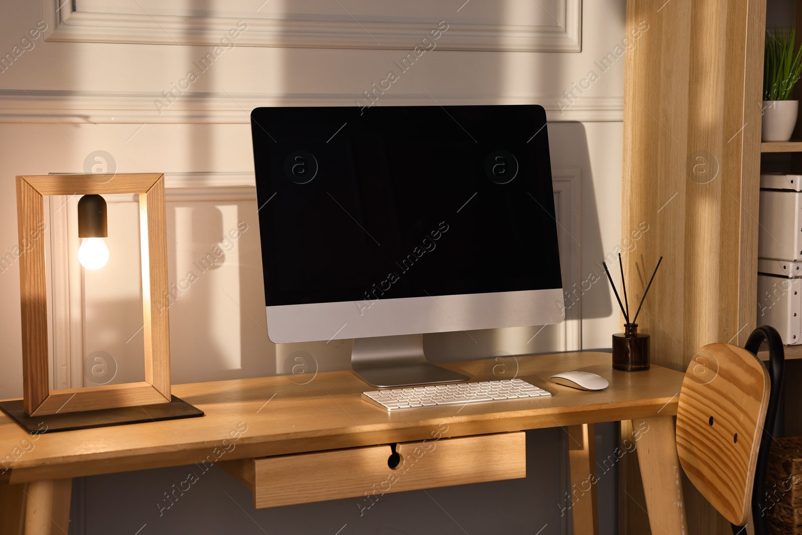Comfortable workplace with modern computer and lamp on wooden desk in home office Photo of Comfortable workplace with modern computer and lamp on wooden desk in home office