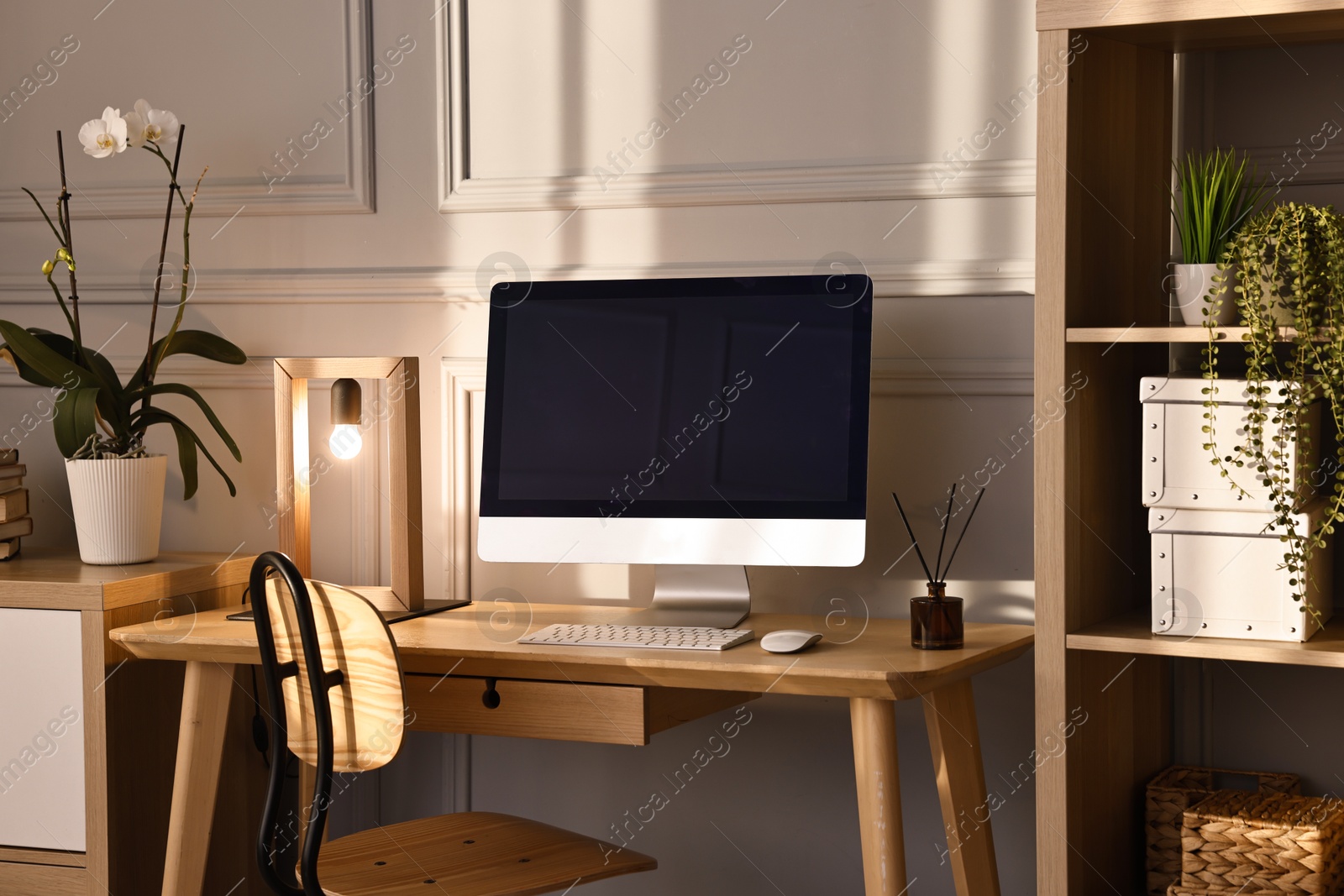 Comfortable workplace with modern computer and lamp on wooden desk in home office Photo of Comfortable workplace with modern computer and lamp on wooden desk in home office