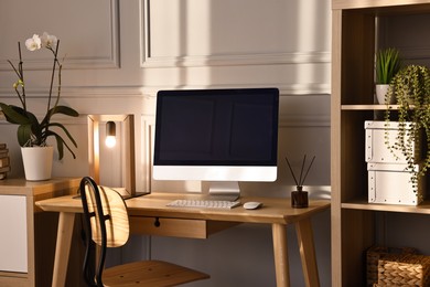 Photo of Comfortable workplace with modern computer and lamp on wooden desk in home office