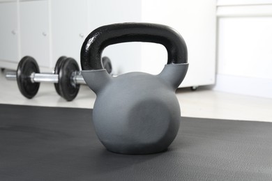 Photo of One kettlebell on mat in gym, closeup