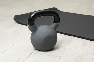 Photo of One heavy kettlebell and mat on floor indoors. Sport equipment