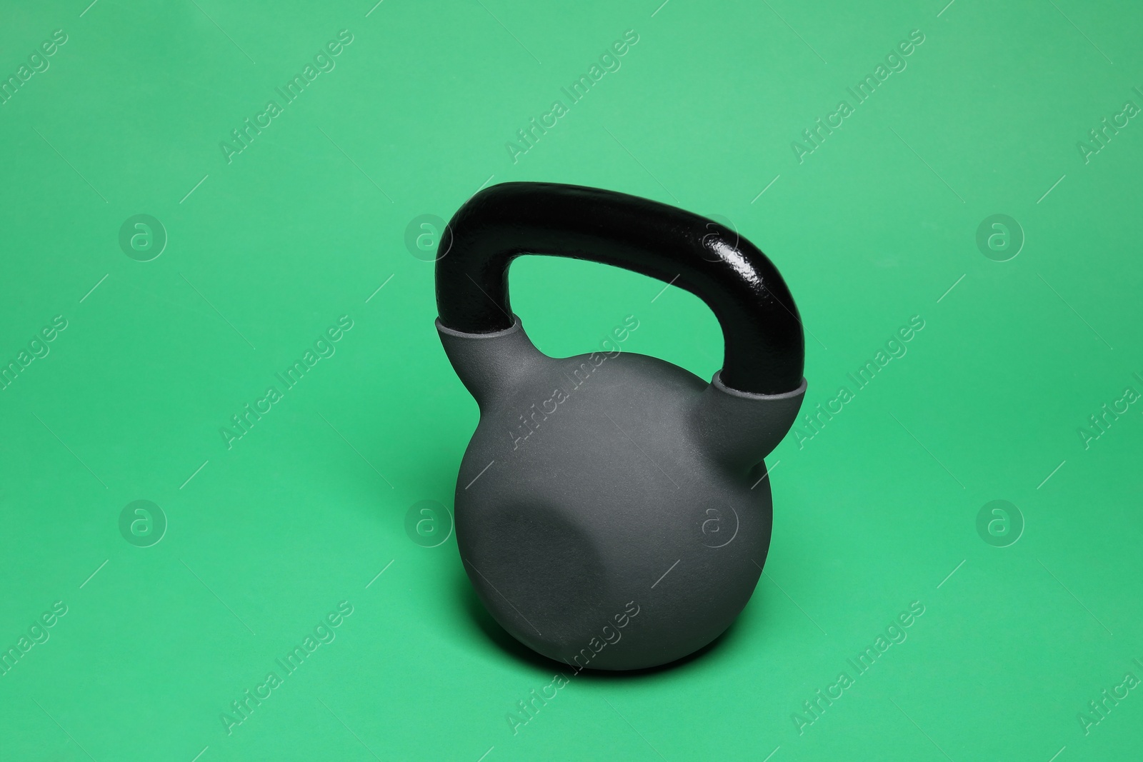 Photo of One heavy kettlebell on green background. Sport equipment