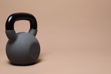 Photo of One heavy kettlebell on beige background. Space for text