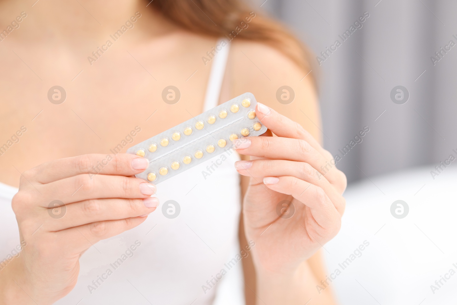 Photo of Woman with blister of contraceptive pills indoors, closeup