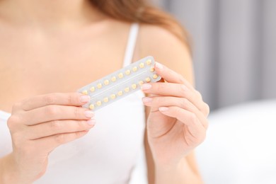 Photo of Woman with blister of contraceptive pills indoors, closeup