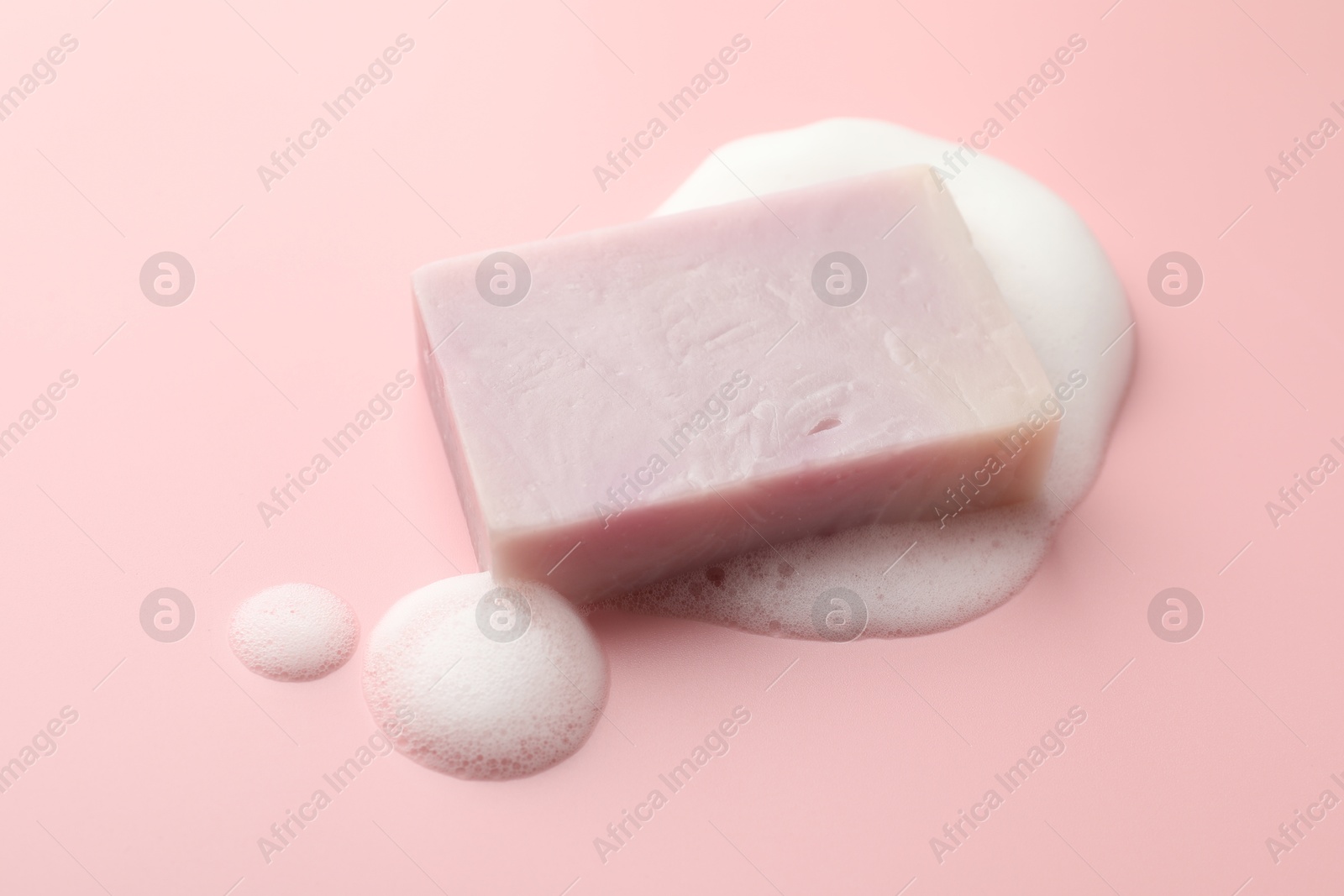 Soap bar with foam on light pink background, closeup Photo of Soap bar with foam on light pink background, closeup