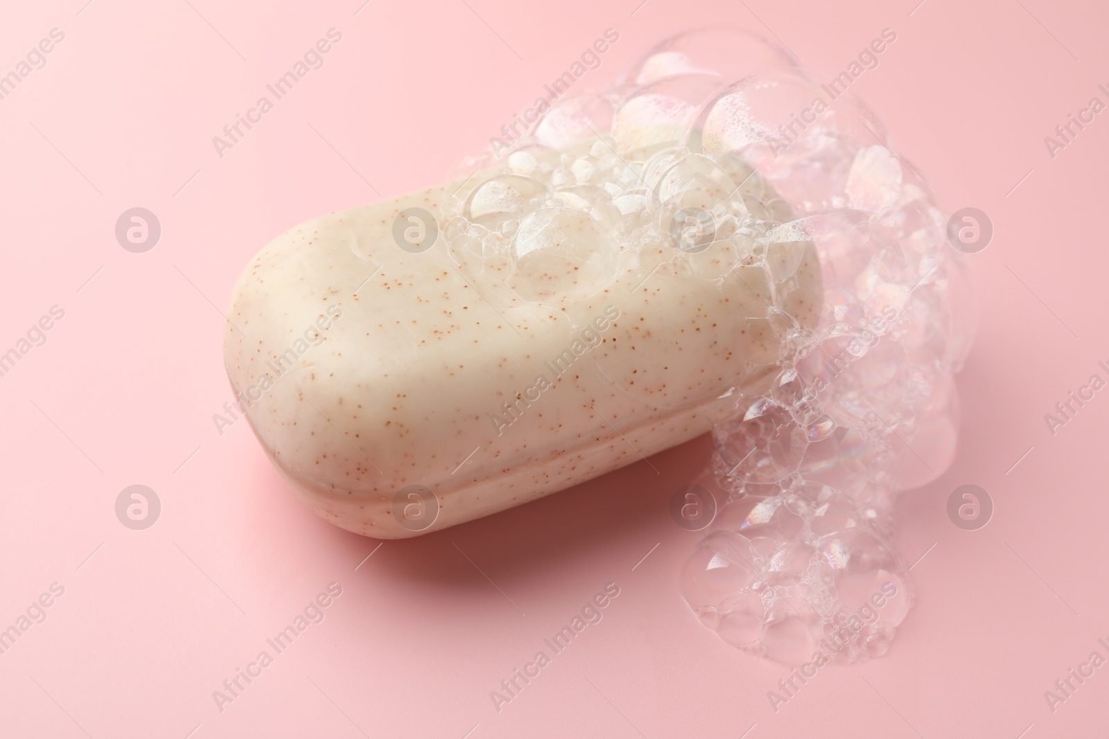 Soap bar with foam on light pink background, closeup Photo of Soap bar with foam on light pink background, closeup