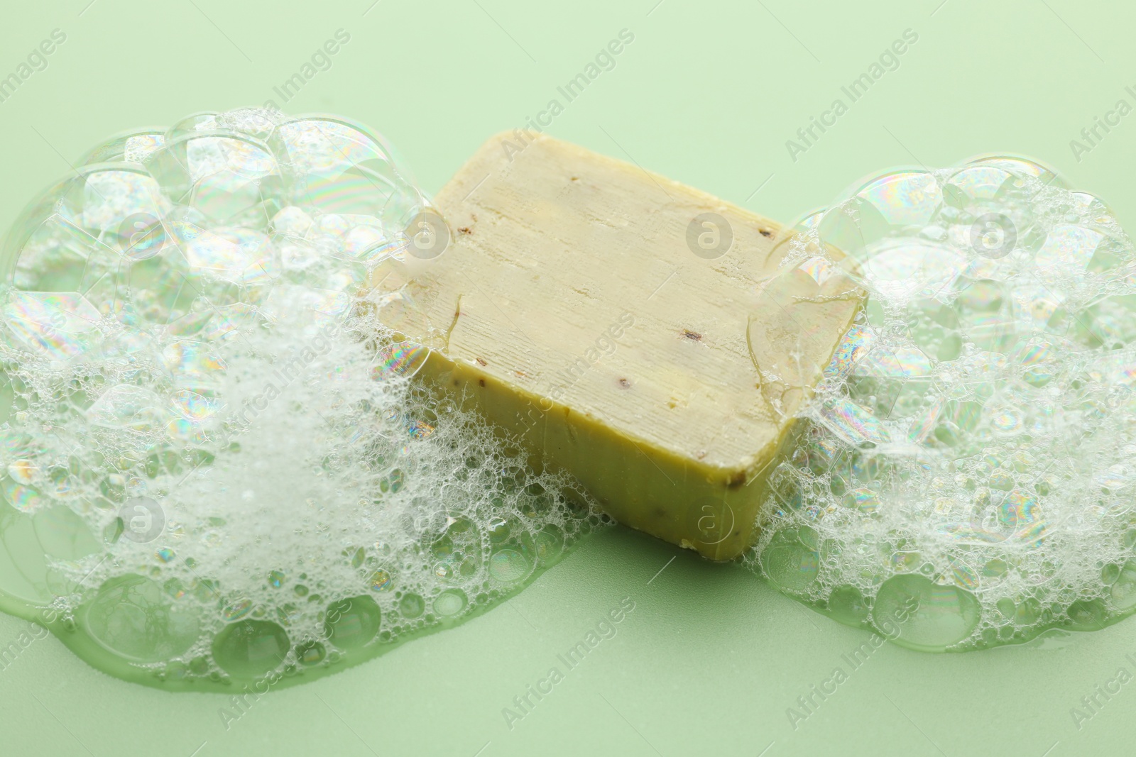 Soap bar with foam on green background Photo of Soap bar with foam on green background