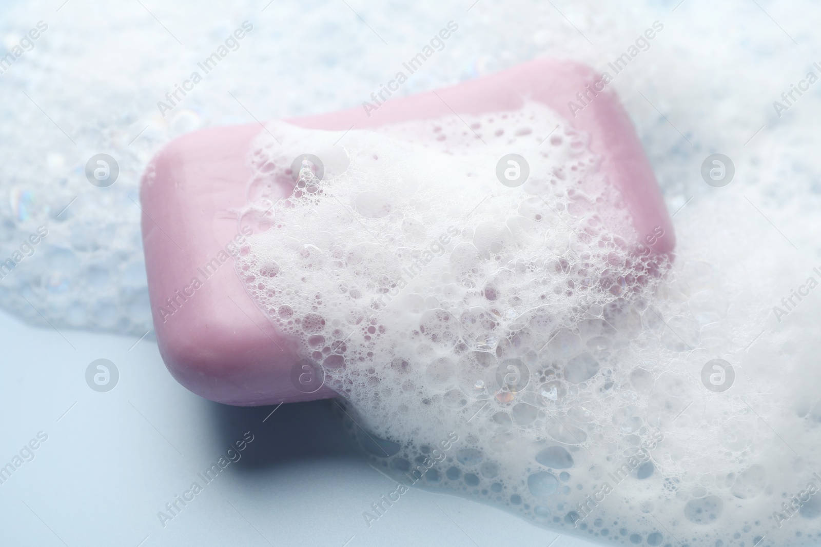 Soap bar with foam on light blue background, closeup Photo of Soap bar with foam on light blue background, closeup