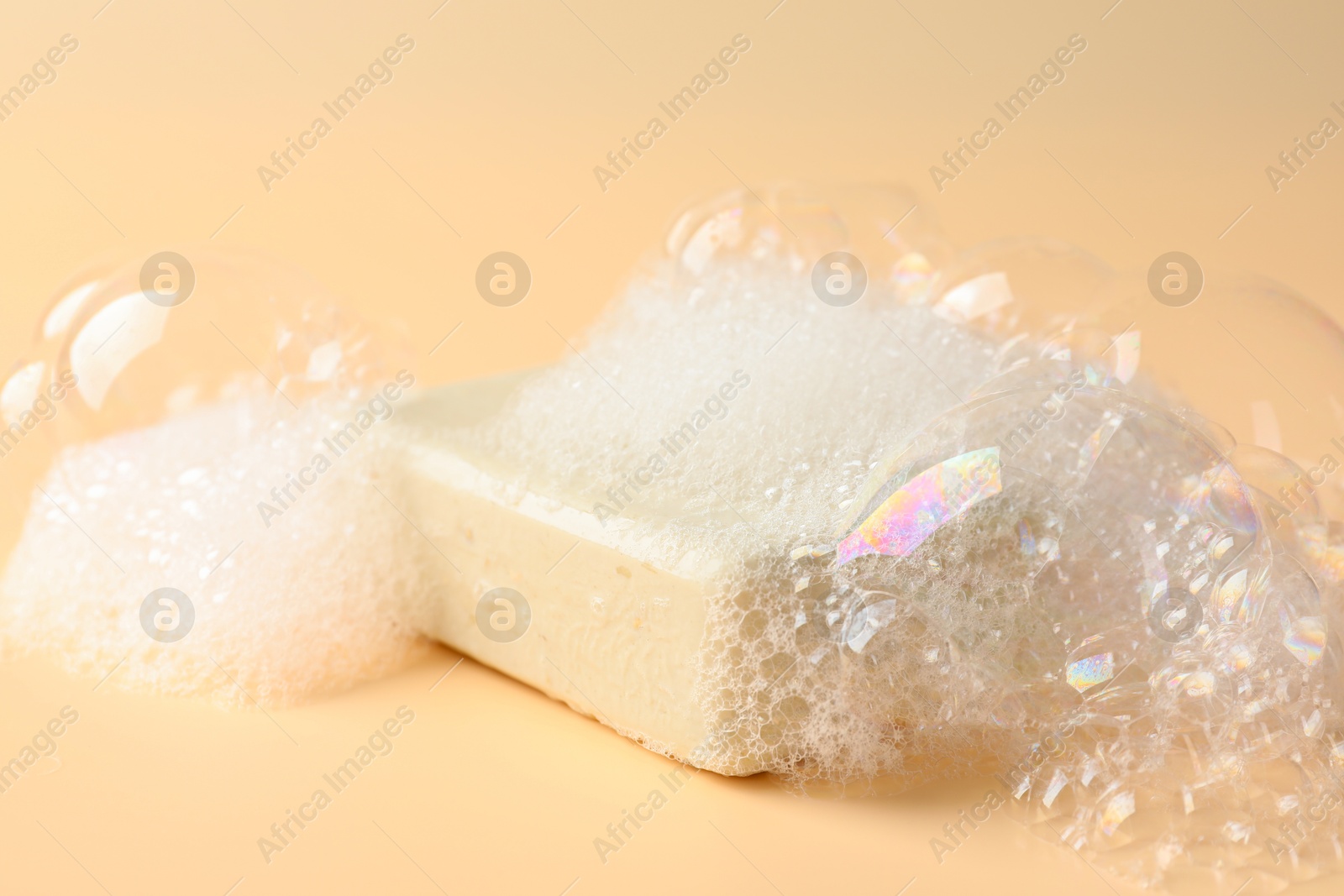 Soap bar with foam on beige background, closeup Photo of Soap bar with foam on beige background, closeup