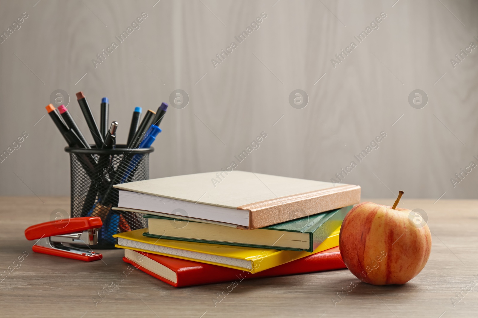 Photo of Doing homework. Notebooks, apple and stationery on wooden desk. Space for text