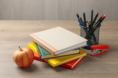 Photo of Doing homework. Notebooks, apple and stationery on wooden desk