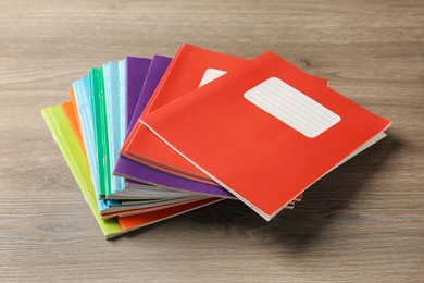 Photo of Doing homework. Stack of notebooks on wooden desk, closeup