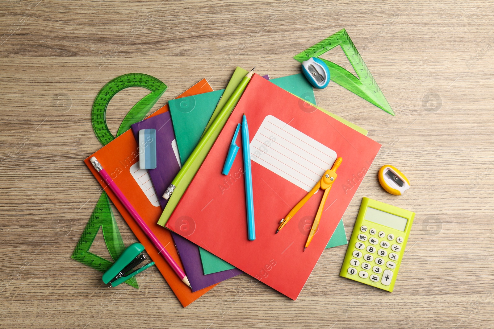 Photo of Doing homework. Copybooks and other different stationery on wooden table, flat lay