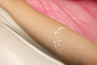 Photo of Woman with moisturizing lotion on her arm after depilation procedure in beauty salon, closeup