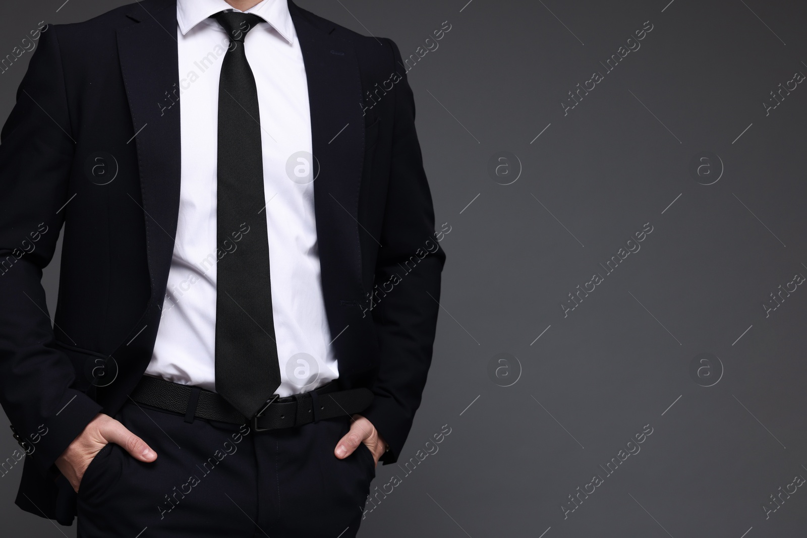 Photo of Man in classic suit on grey background, closeup. Space for text