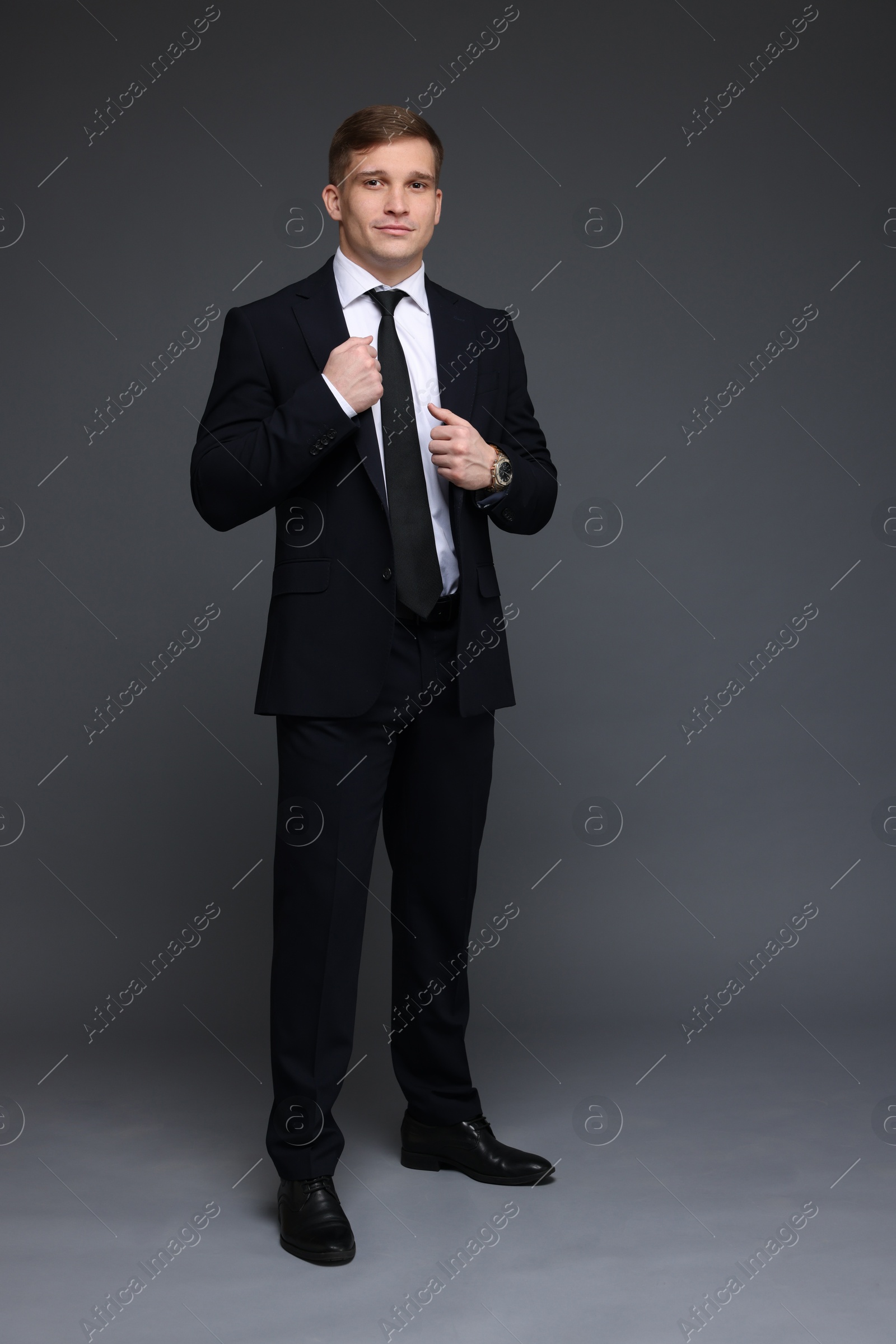 Photo of Man in classic suit with stylish watch on grey background