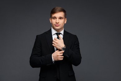 Man in classic suit with stylish watch on grey background