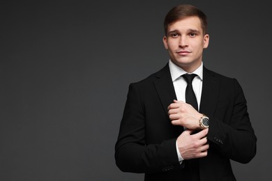 Man in classic suit with stylish watch on grey background. Space for text