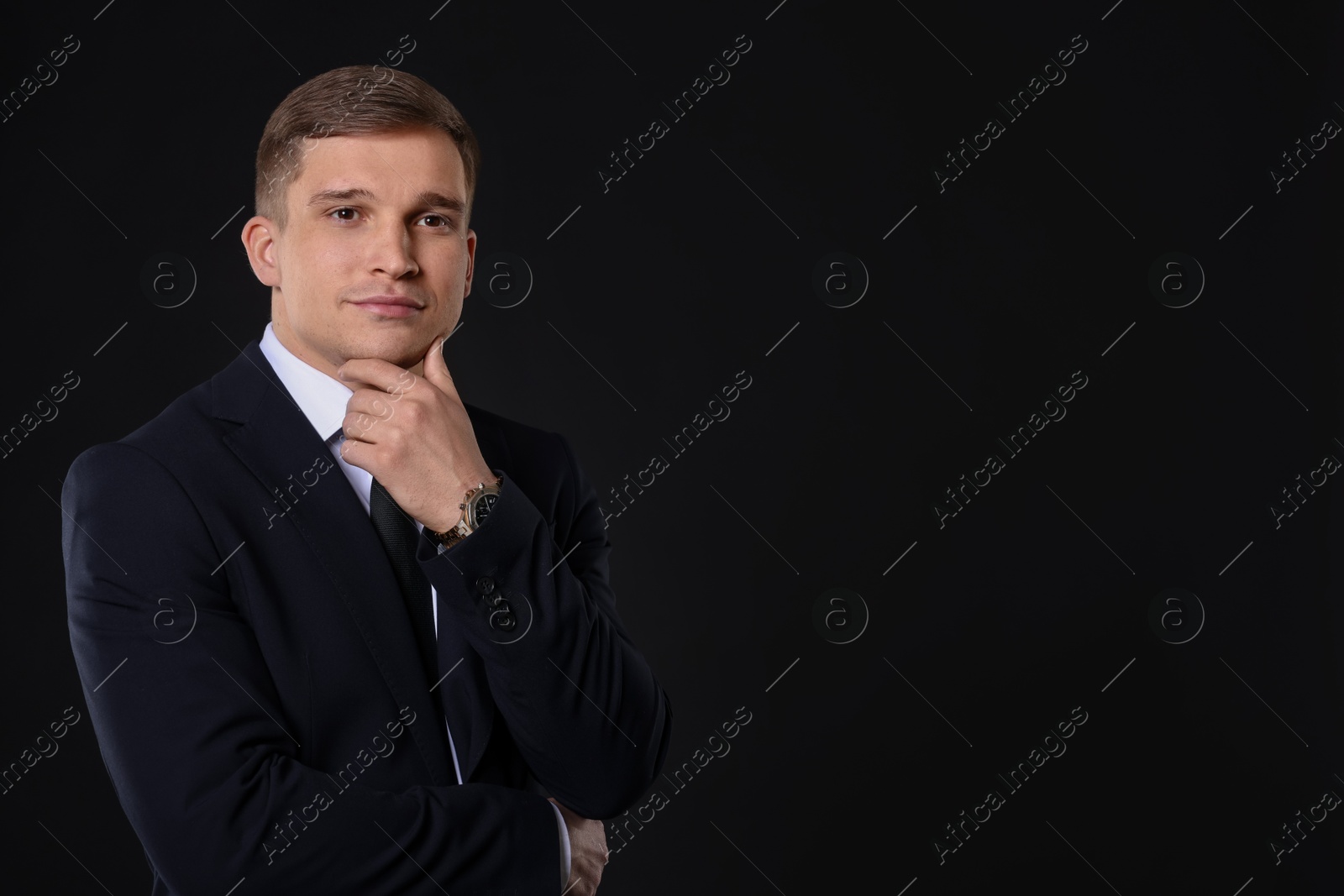 Photo of Man in classic suit on black background. Space for text