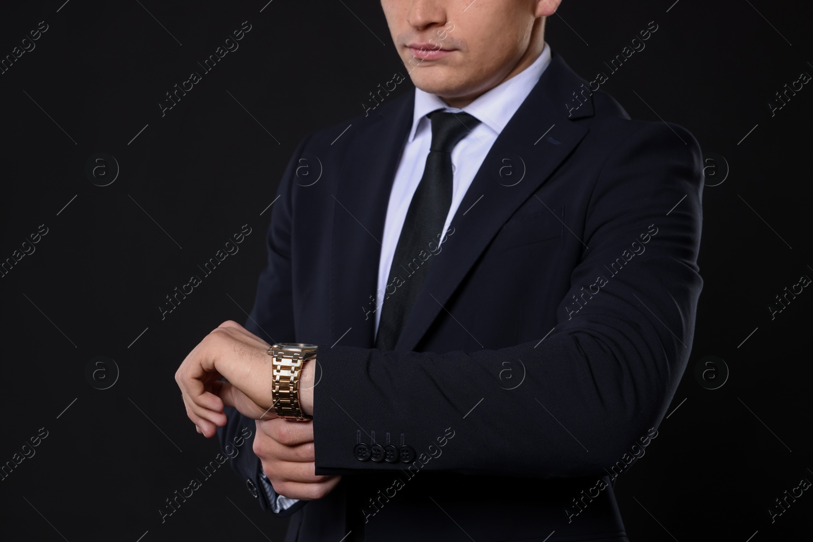 Photo of Man in classic suit with stylish watch on black background, closeup