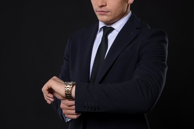 Man in classic suit with stylish watch on black background, closeup