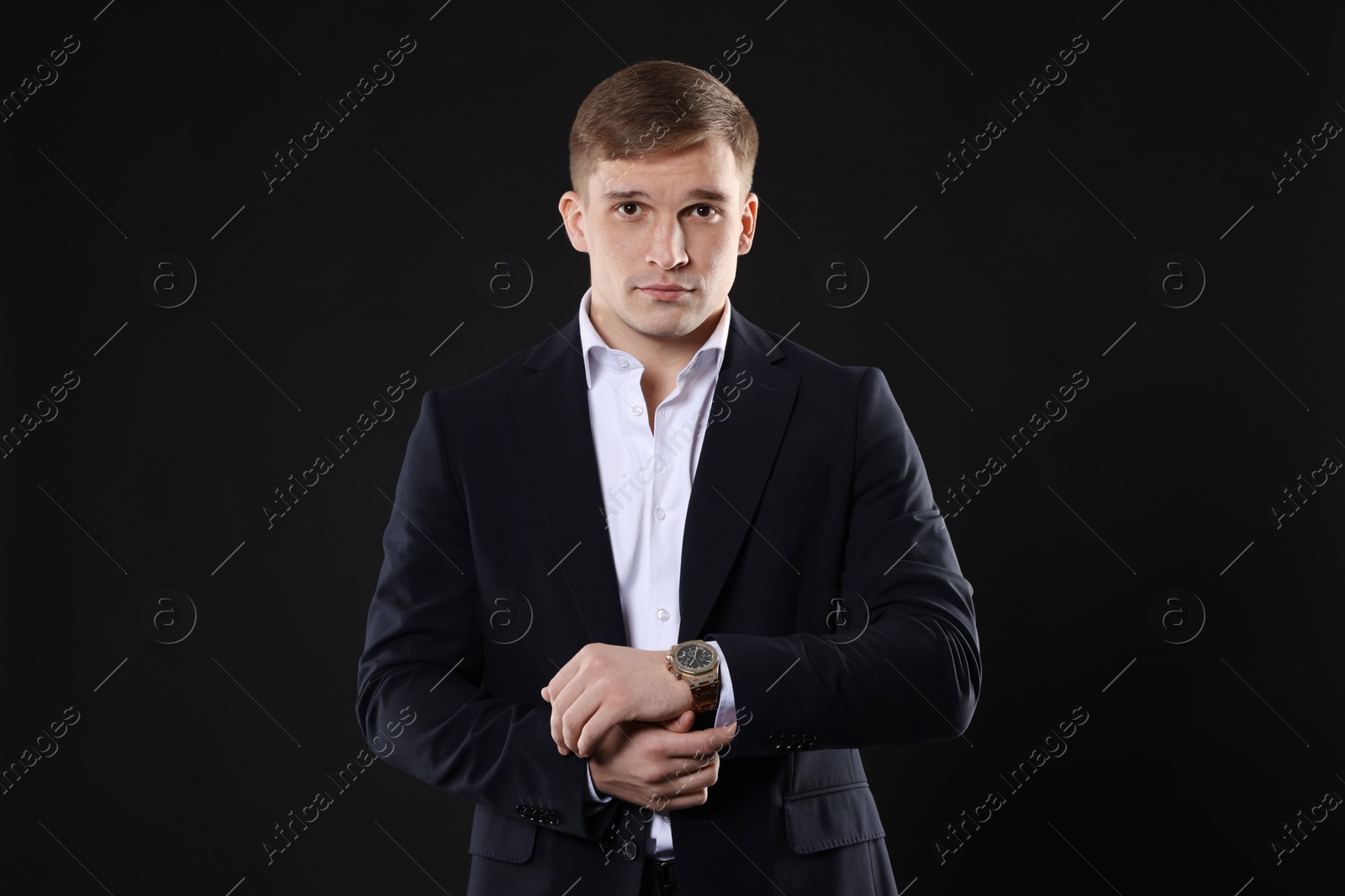 Photo of Man in classic suit with stylish watch on black background