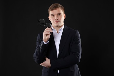 Man in classic suit with glasses on black background