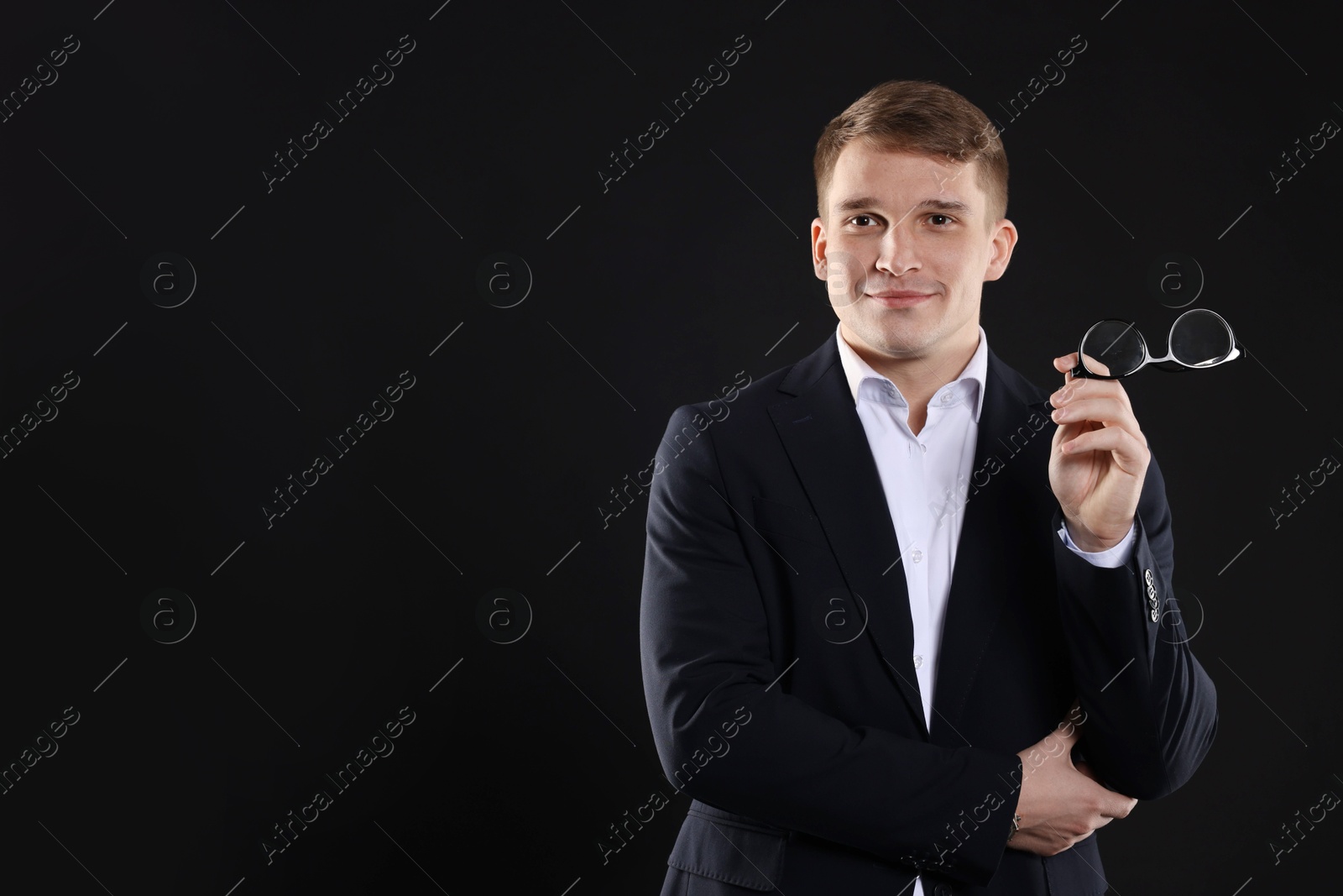 Photo of Man in classic suit with glasses on black background. Space for text