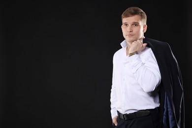 Photo of Man in classic suit on black background. Space for text