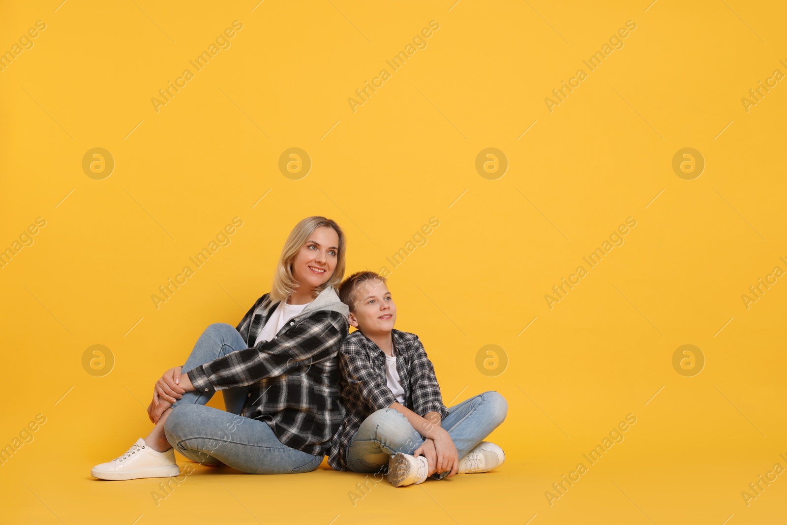 Photo of Happy mother and son on orange background. Space for text