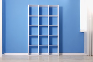 Photo of Empty shelving unit near blue wall indoors